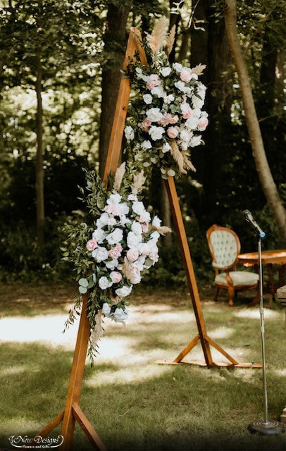 A Triangular Wooden Arch, with White Material, and Rustic Floral installments, of White and Nude Roses, with Pampas Grass